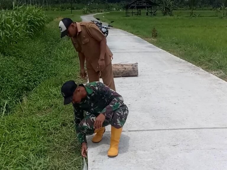 Anggota Satuan Tugas (Satgas) TMMD, Sertu Farid, bersama Kepala Dusun Sukomaju, Desa Lebakharjo, Kecamatan Ampelgading, meninjau langsung hasil pekerjaan jalan rabat beton yang telah selesai 100 persen