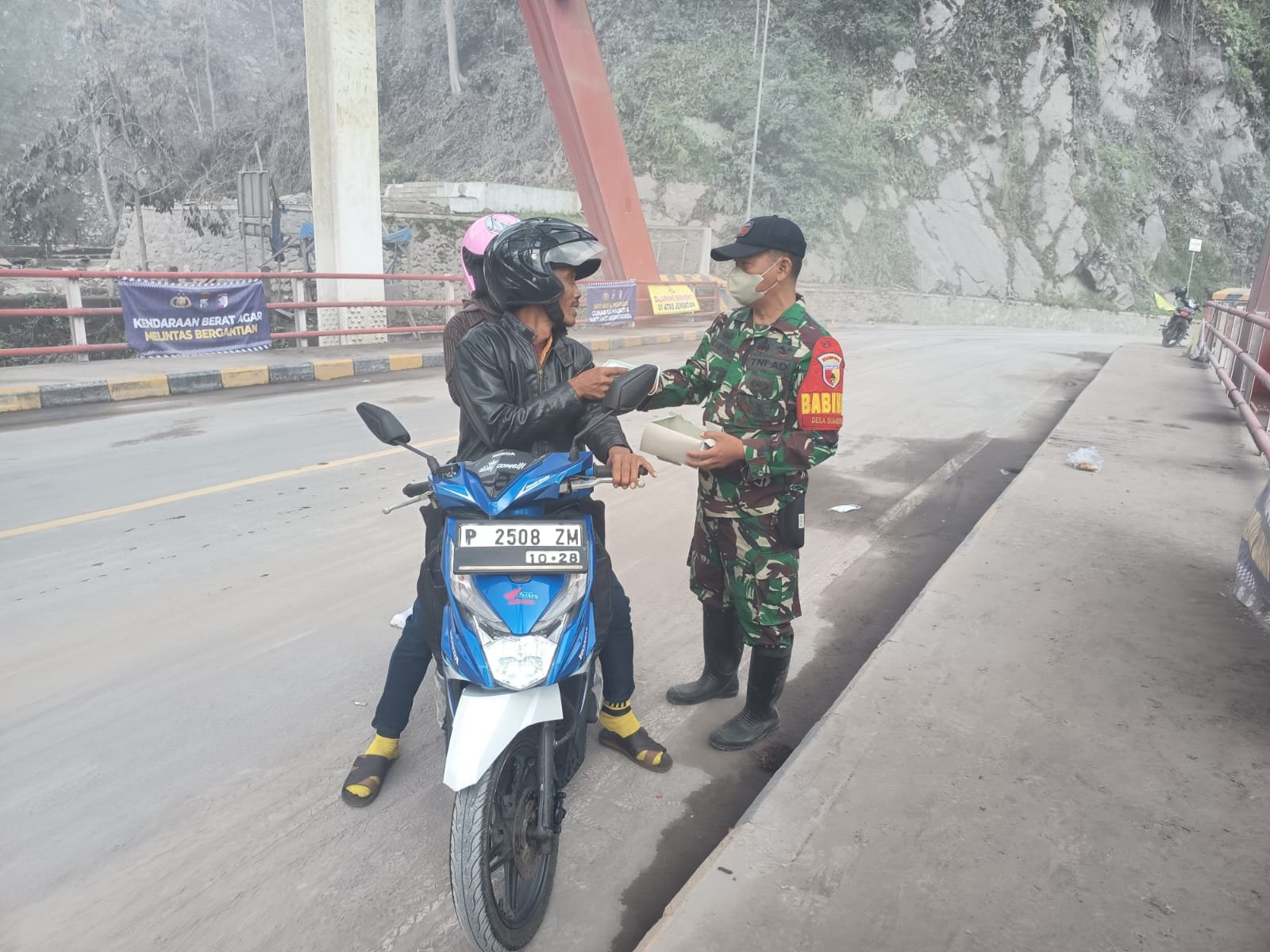 Babinsa Sumberwuluh Amankan Lalin dan Lindungi Pengendara dengan Pembagian Masker
